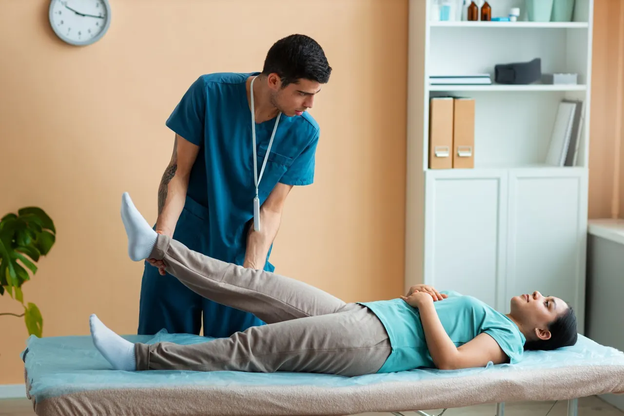 Illustrative photograph of a physiotherapist guiding a patient through a leg stretch